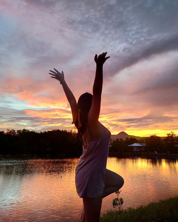 Person standing in a balanced yoga pose against a minimal background.
